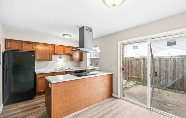 A kitchen with a black fridge and wooden cabinets.