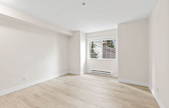 A room with a window and a wooden floor.