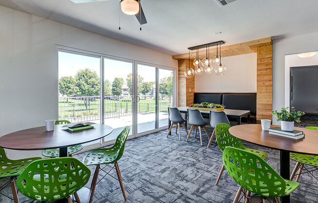 One BR Apartments in Ontario, CA - Veranda Ontario - Clubhouse with Dining Areas, Large Sliding Glass Doors Leading to Patio, and Hanging Light Fixtures