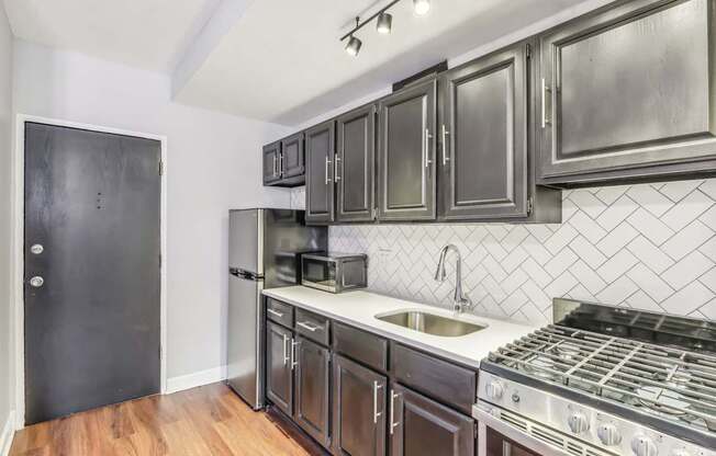 A kitchen with a black door and a black fridge.
