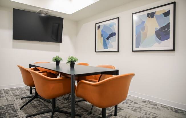a meeting room with a table and chairs and a tv on the wall