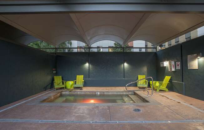 a hot tub and green chairs in a room with a window