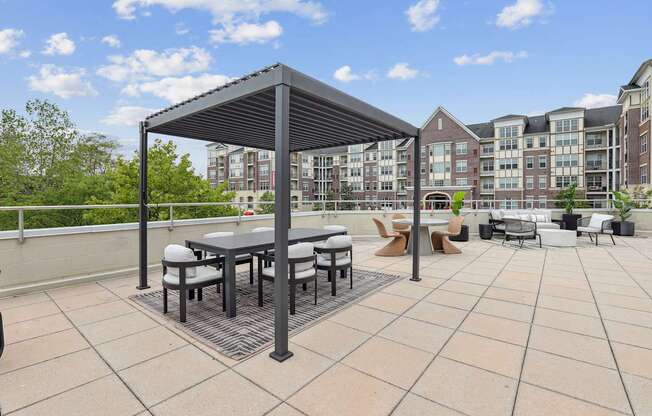 A patio with a table and chairs under a black canopy.