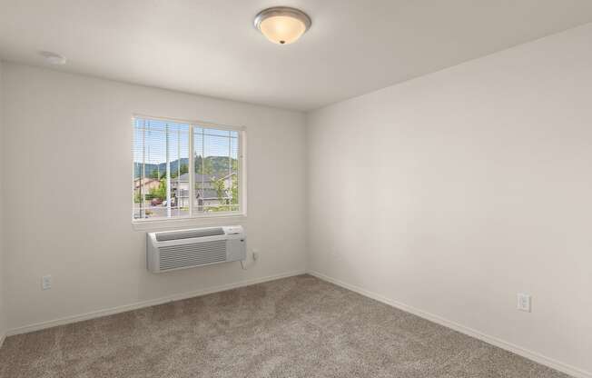 an empty room with a window and an air conditioner