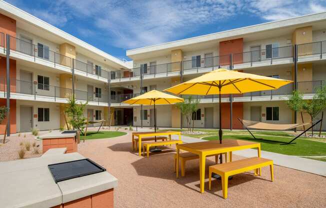 a courtyard with yellow tables and yellow umbrellas