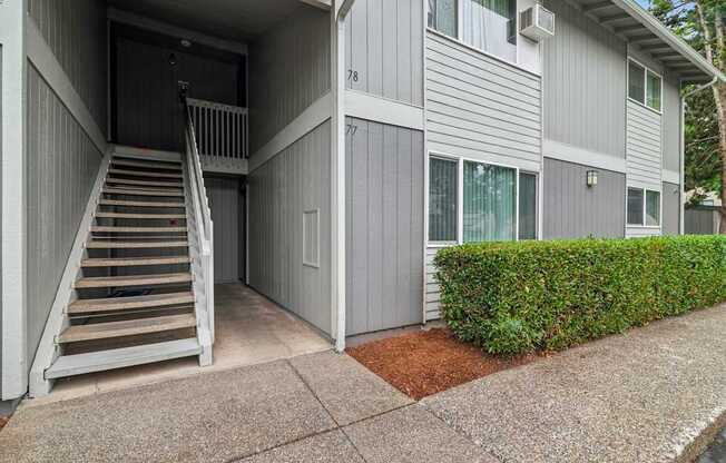 A grey building with a staircase leading to a door.