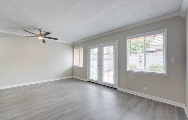 A room with a ceiling fan and sliding glass doors.