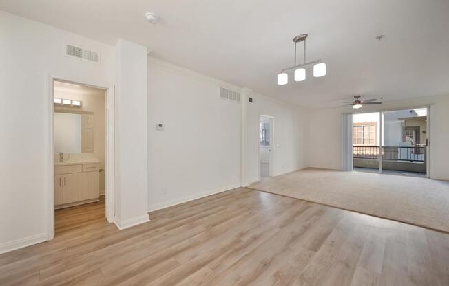 A spacious room with wooden flooring and white walls.