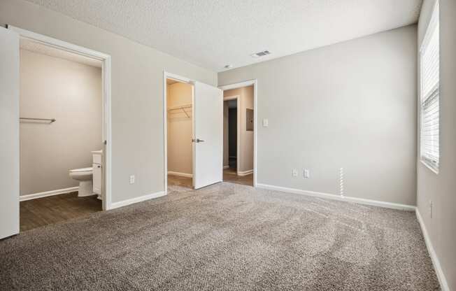 a bedroom with an open door and a bathroom in the background