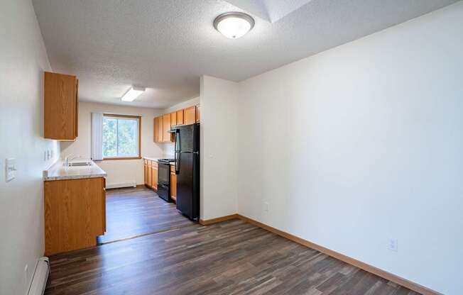 A kitchen with a refrigerator, sink, and cabinets. Bismarck, ND Sierra Ridge Apartments