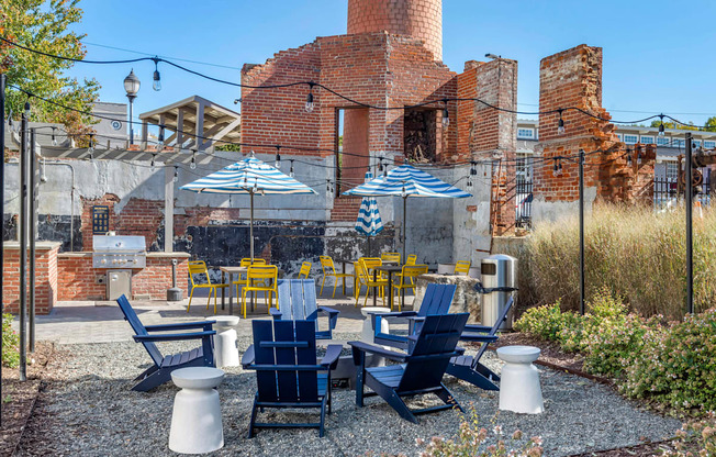 a patio with blue and yellow chairs and umbrellas at Highland Mill Lofts, Charlotte, North Carolina