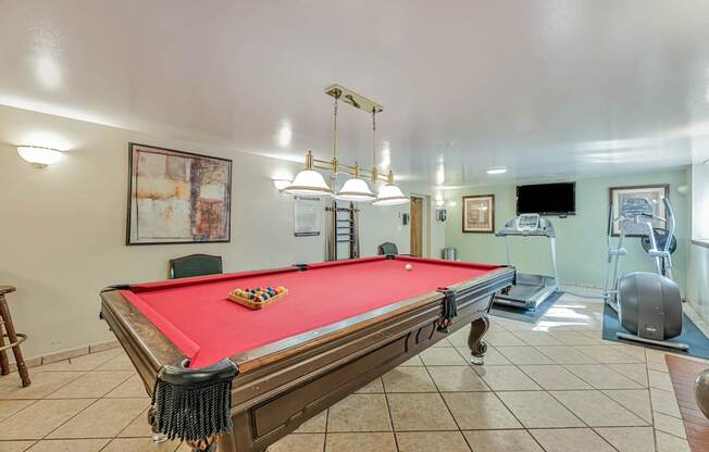 A pool table with a red cloth and a set of pool balls on it.