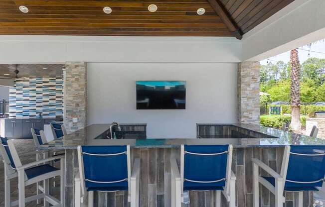 A wooden table with blue chairs and a television on the wall.