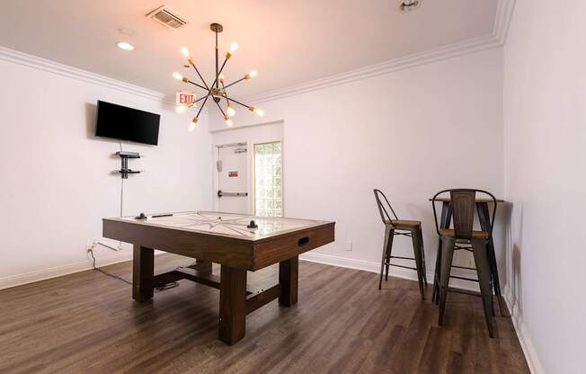 A room with a pool table and chairs.