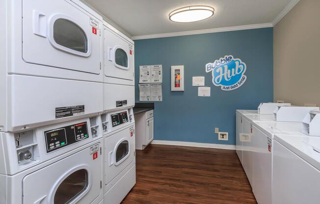 Laundry room with white washers and dryers at Ashley Oaks Apartments in Greensboro, North Carolina