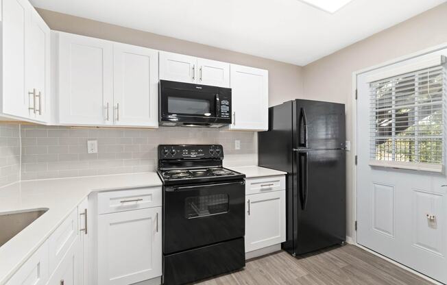 a kitchen with white cabinets and black appliances