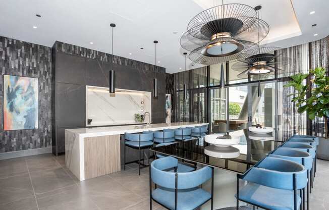 a kitchen and dining area with blue chairs and a long black table