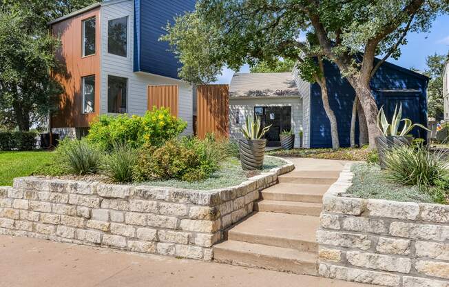 a stone retaining wall in front of a house with stairs