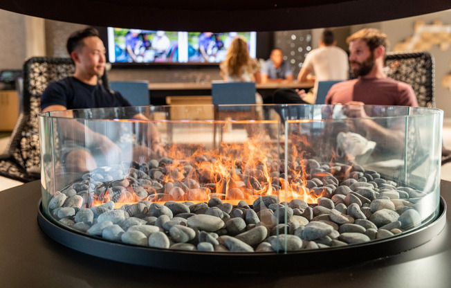 Clubhouse - people around a fire feature and watching TV | The Q | Quincy, Massachusetts Apartments