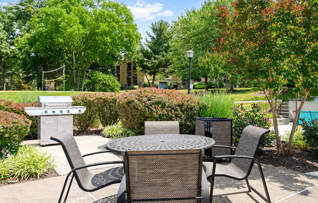 a patio with a table and chairs and a grill