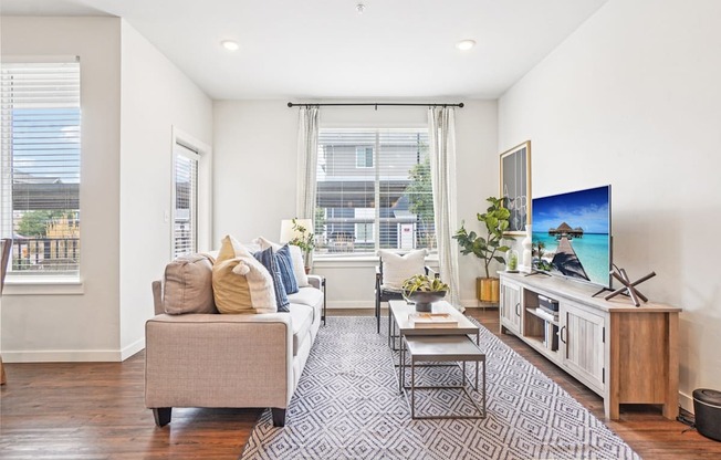 A living room with a couch, a coffee table, and a television. at Connect at First Creek Apartments, Denver, Colorado