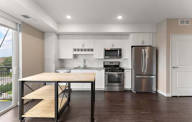 A kitchen with a table and stainless steel appliances.