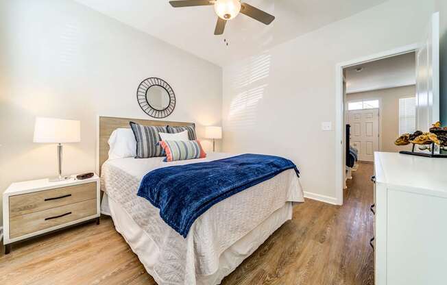 A bedroom with a bed, nightstand, and a ceiling fan.