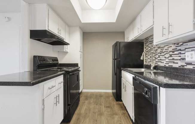 an empty kitchen with black appliances and white cabinets