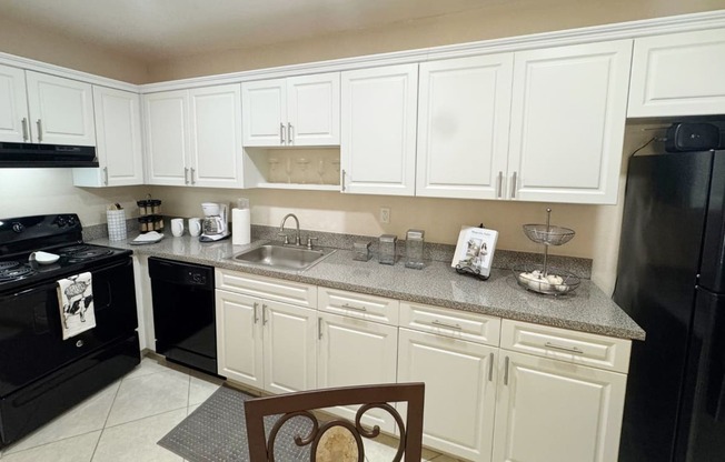 a kitchen with white cabinets and black appliances