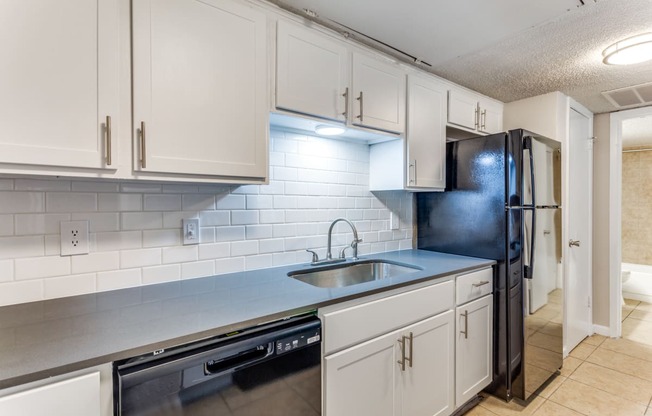 a kitchen with white cabinets and a sink and a refrigerator