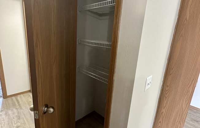 a walk in closet in a bedroom with a wooden door and white walls