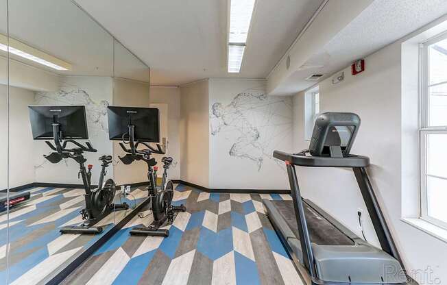 A treadmill and two stationary bikes are in a room with a world map on the wall.