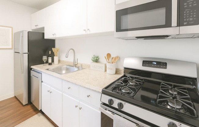 A modern kitchen with a black fridge, white cabinets, and a white stove top oven.