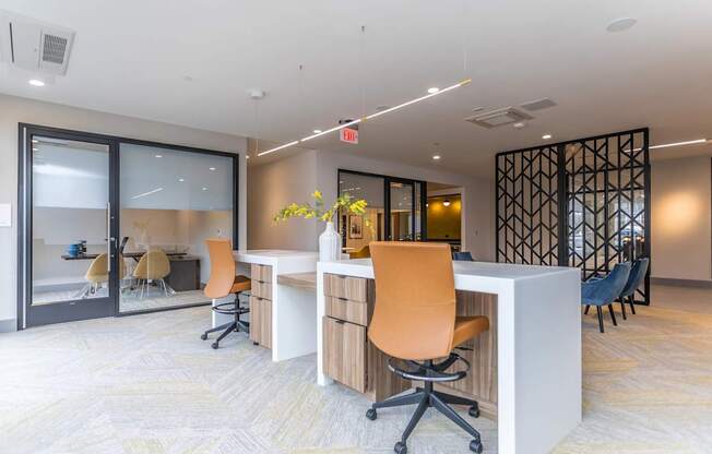 A modern office space with a white desk and orange chairs.