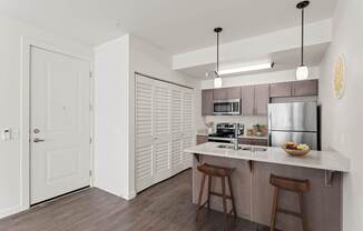 A kitchen with a white counter top and wooden floors.