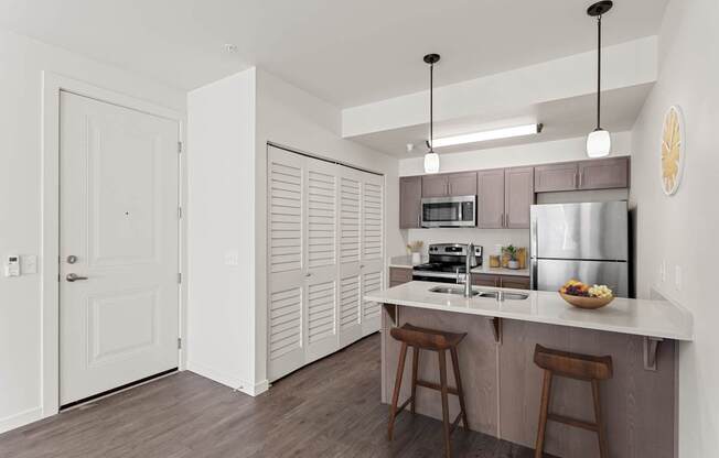 A kitchen with a white counter top and wooden floors.