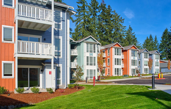 an exterior view of a row of apartment buildings with green grass at Woodcreek, Poulsbo Washington