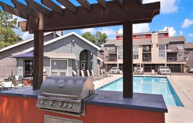 A barbecue grill is on a table next to a pool.