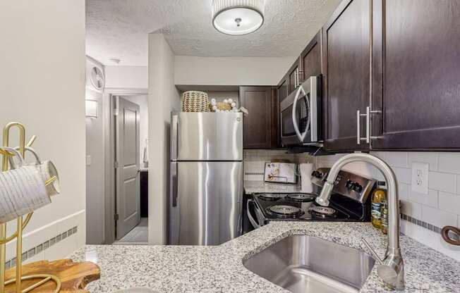 A kitchen with a stainless steel refrigerator, microwave, and oven.