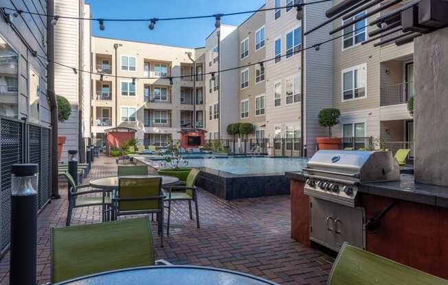 a patio with tables and chairs and a pool in front of an apartment building
