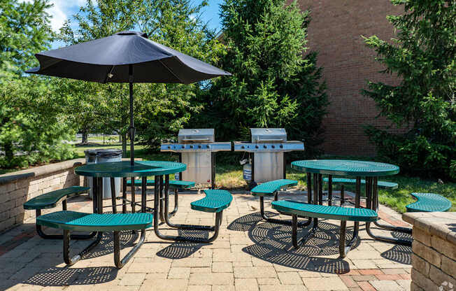A patio with tables and chairs and a blue umbrella.