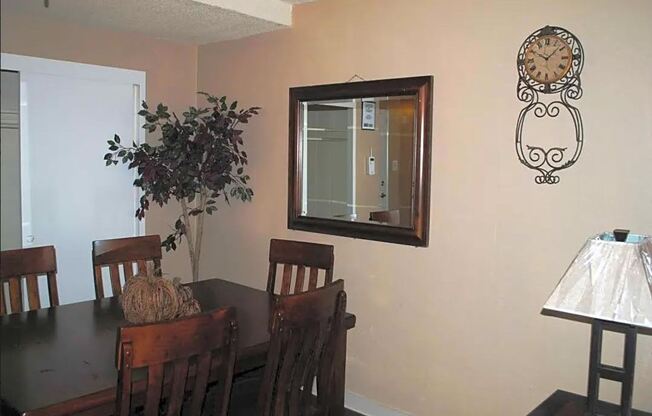 a dining room with a table and chairs and a clock on the wall