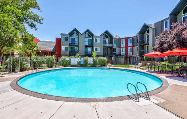 A swimming pool in front of a multi-story apartment building.