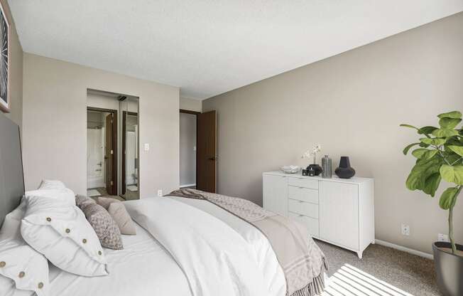 a bedroom with a large white bed and a white dresser