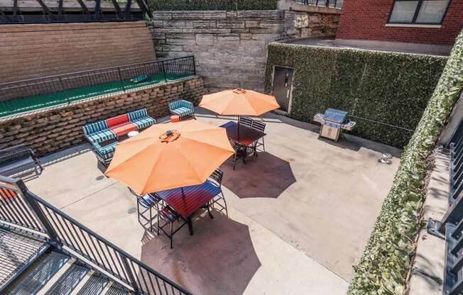 Outdoor patio with sun umbrellas, different seating, and a grill