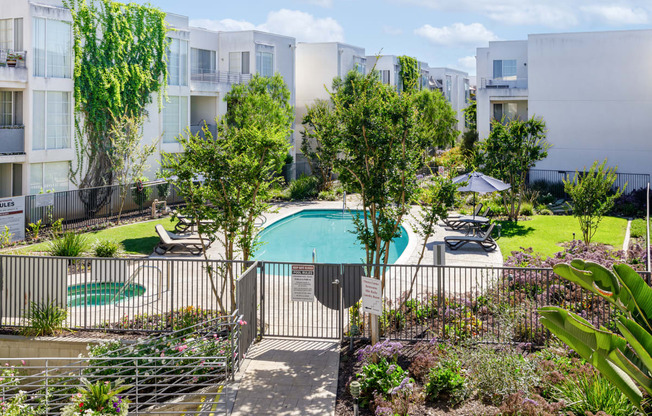 an apartment building with a swimming pool and trees in front of it