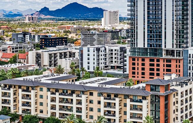 A cityscape with buildings of various designs and a mountain in the background.