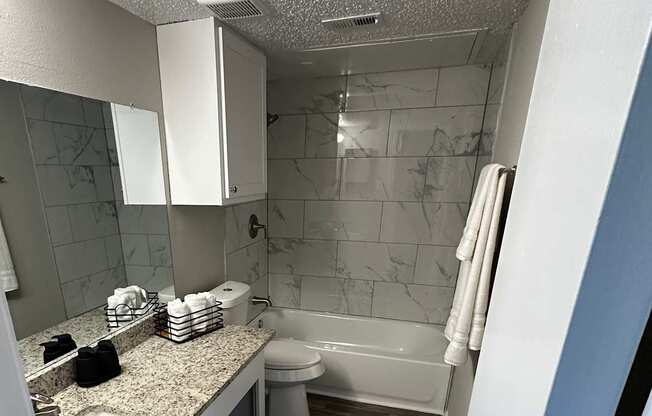 A bathroom with a toilet, sink, and mirror.