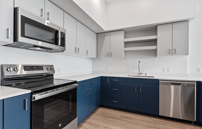 a kitchen with blue and white cabinets and stainless steel appliances