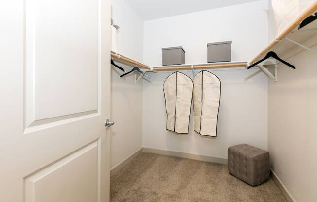 a walk in closet with a pair of folded towels and a stool